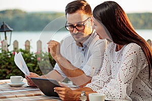 Two happy young freelancers working in a restaurant by the river