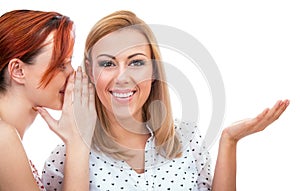 Two happy young girl friends whispering