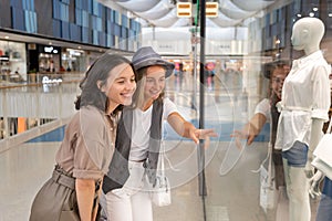 Two happy young girlfriends walking in shopping mall