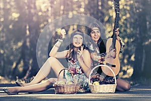 Two young fashion girls with fruit baskets in summer forest