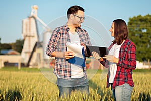 Two happy young male and female farmers or agronomists inspecting a wheat field before the harvest photo