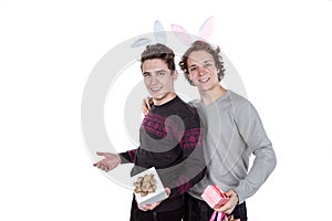 Two happy young men in a rabbit-like ears holding up gift boxes. Isolated on white background