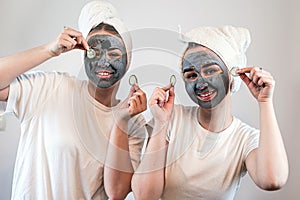 Two happy young woman apply clay mask on face enjoy free time