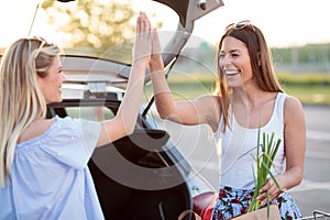 Two happy young women giving each other high-fives after a fun day of shopping