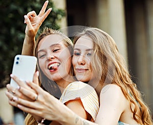 Two happy young women together taking a selfie in the city. Summer day. Friendship concept.