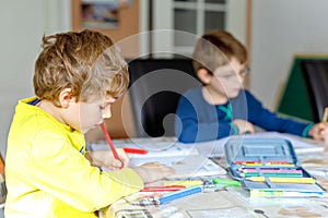 Two hard-working school kids boys making homework during quarantine time from corona pandemic disease. Children