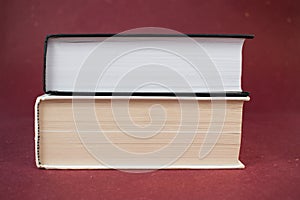 Two hardcover books stacked together on red background.