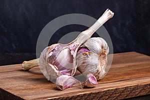 Two heads of garlic lie on a wooden board !