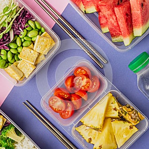 Two healthy asian-style plant-based lunch boxes knolled together on blue and pink background