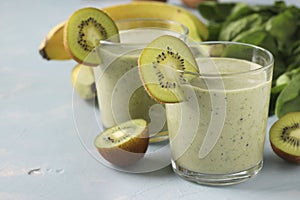 Two healthy detox smoothie kiwi, banana, spinach in glasses on light blue background with fresh ingredients, Diet and weight loss