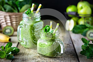 Two healthy green smoothie with spinach, banana, apple, kiwi and mint in glass jar.