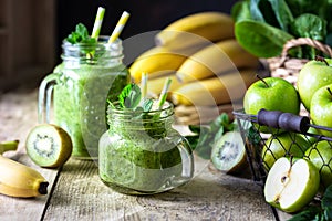 Two healthy green smoothies with spinach, banana, apple, kiwi and mint in glass jar and ingredients. Detox, diet, healthy,