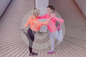 Two healthy young female sporty women prepairing for running in morning on street. Runner training outdoors in morning