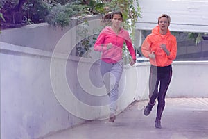 Two Healthy young female sporty women running in morning on street. Runner training outdoors in morning