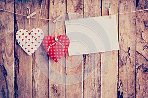 Two heart fabric and paper hanging on clothesline at wood background with space.