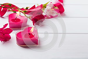 Two heart shaped candles on the white wooden table