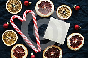 Two heart-shaped candycanes next to dried citrus fruits, Christmas tree decorations and a notepad for notes