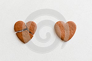 Two heart shaped cookies, one of them is broken on a white background. Crack heart-shaped cookies as a concept of breaking and