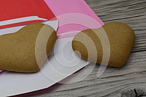two heart shaped cookies, purple and red envelopes on a wooden rustic background. Valentine's Day, greeting card, pastry