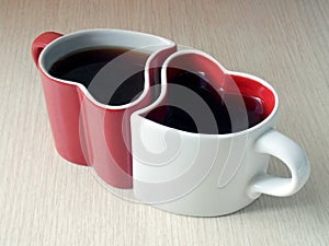 Two heart-shaped cups of tea on a wooden table