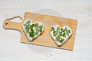 Two heart-shaped sandwiches with cottage cheese and parsley