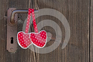 Two heart shapes hanging on an old door handle with polka dots o