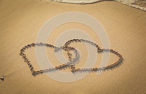 Two hearts drawn on sand beach