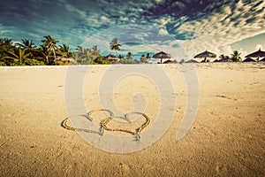 Two hearts drawn on sand of a tropical beach. Vintage