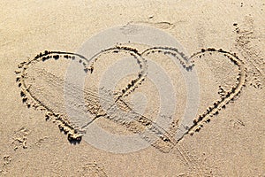 two hearts drawn on the sea sand