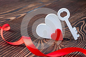 Two hearts with a key and ribbon on wood background