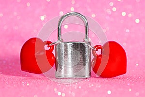 Two hearts locked together with a padlock on pink