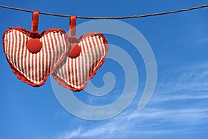 Two Hearts made of Cloth against a Blue Sky with Clouds and Copy Space