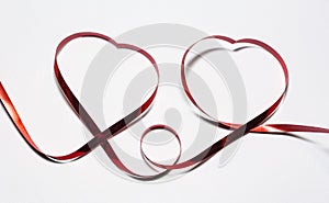 Two hearts of red ribbon on white background