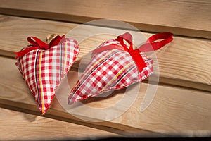 Two hearts sewn from red plaid fabric on the board