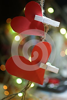 Two hearts on a string. Red blank paper with love symbol shape hanging on rope with white wooden clips and colorful bokeh lights.