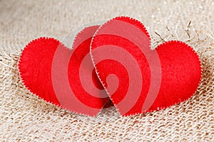 Two hearts symbol of love on burlap background.