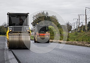 Two heavy road rollers compacting asphalt surface during construction work