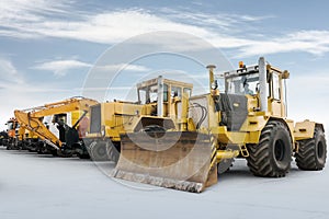 Two heavy wheeled tractor one excavator and other construction machinery isolated on bright