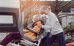 Two helpers picking up disabled senior woman for transport