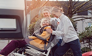 Two helpers picking up disabled senior woman for transport photo