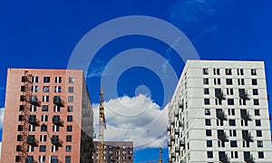 Two high-rise buildings under construction against a bright blue sky