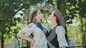 Two high school senior girls playfully sort of kissing.