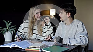 Two high school students, a boy and a girl, are preparing for college lectures together. Teenagers listen to music