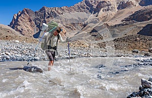 Two hikers crossing mountain river