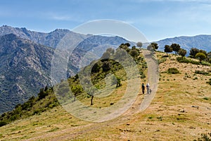 Two hikers and dog on trail near Novella in Balagne region of Co