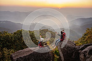 Two hikers happy on top of hill and enjoying sunset over the valley at thailand