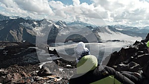 Two hikers having a rest on a mountain top. Clip. Travelers in bright clothes sitting together and enjoying a wonderful