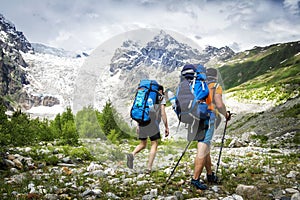 Two hikers with large backpacks in mountains. Tourists hike on rocky mounts. Leisure activity on mountain trek