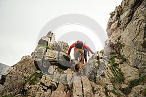 Two hikers scrambling up a rocky mountain trail