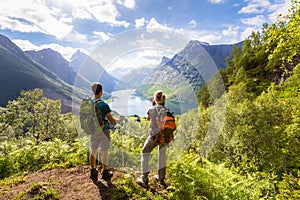 Two hikers at viewpoint  in mountains with lake, sunny summer